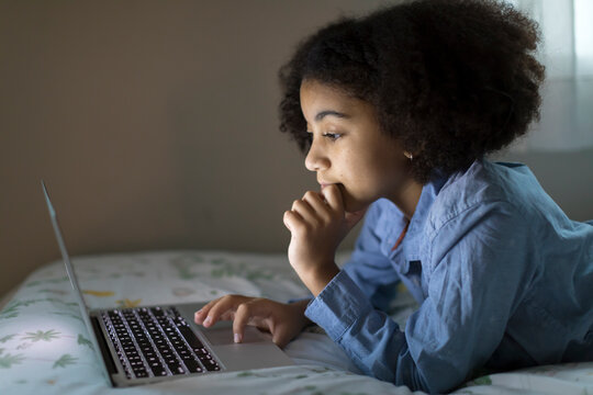 Side view of an ten year-old bi-racial girl working on her laptop