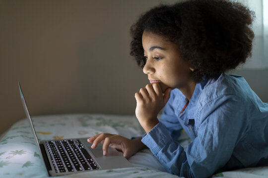 Side view of an ten year-old bi-racial girl working on her laptop