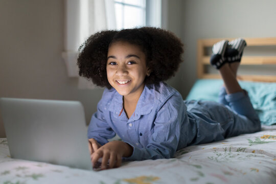 Ten Year-old Bi-racial Girl Working On Apple Laptop Smiling At Camera