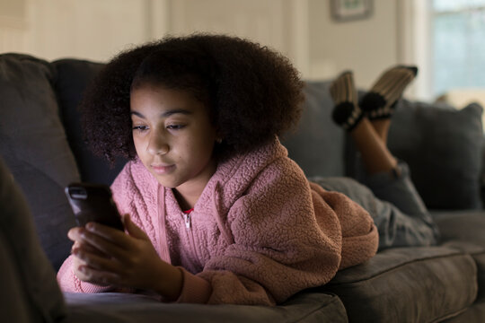 Ten year-old bi-racial girl looking at her cell phone while l