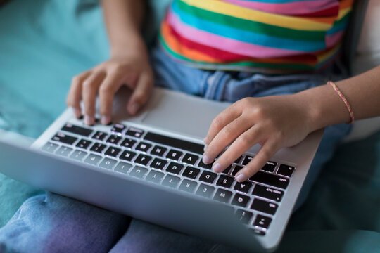 Close up of bi-racial tween girl's hands working on laptop