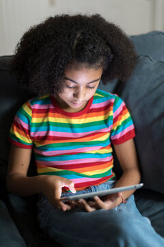 ten year-old bi-racial girl looking at ipad on sofa