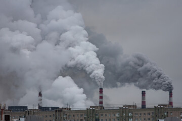 industrial chimneys with heavy smoke causing air pollution on the gray smoky sky background