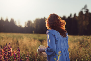 A girl in a field  standing in the rays of the setting sun