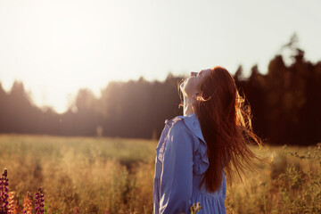 A girl in a field  standing in the rays of the setting sun