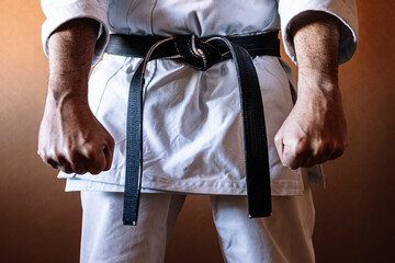 Unrecognizable karateka with black belt in firm position