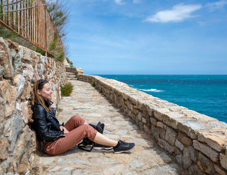 Cheerful girl dressed in red enjoying the coast and looking at the sea