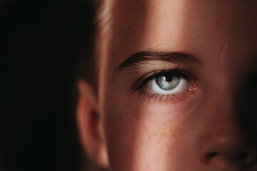 Close up of child's blue eye with black background in beam of light