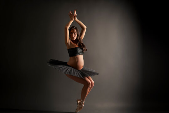 Young pregnant ballerina performing classical ballet pose
