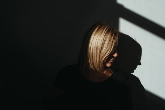 Woman's profile in bright light with black background and shadows