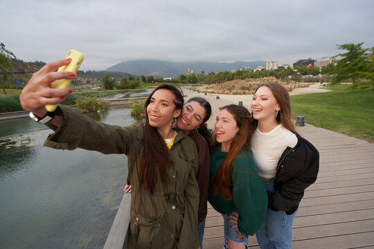 A group of beautiful women take a selfie in the city center park by a
