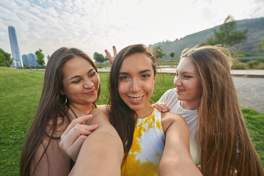 group of teenage friends take a selfie picture in a park while having