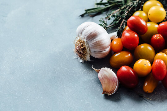 Tomatoes, garlic, and herbs on a wooden board
