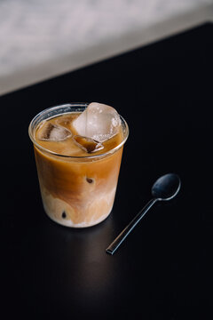 Specialty Coffee Iced Latte On Black Tabletop With Black Spoon