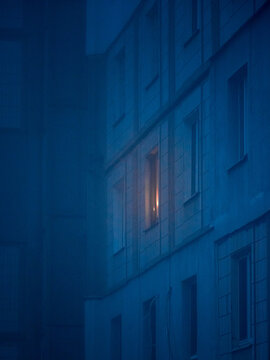 Window of a multistory Soviet building glowing in the fog
