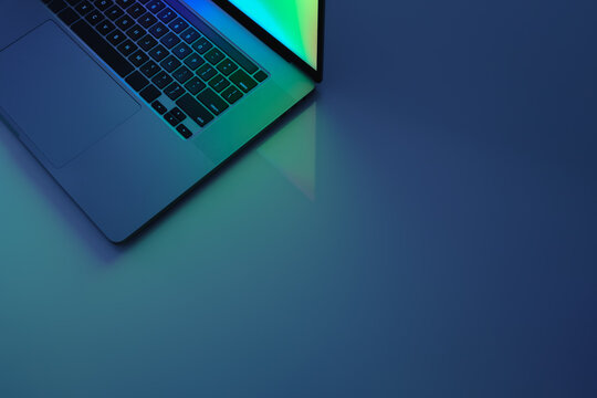 Laptop computer standing on a table, low key blue light image. C