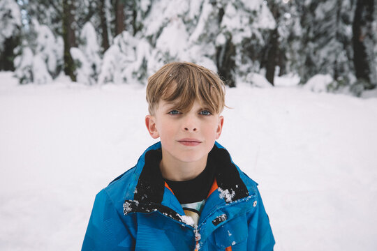 Blonde Boy With Blue Eyes Standing in a Snowy Field