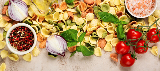 Raw orecchiette with parmesan cheese and tomatoes, basil with garlic and oil on light background....