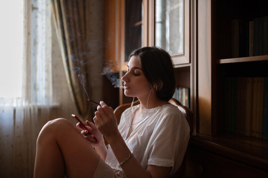 Young woman smoking and using smartphone