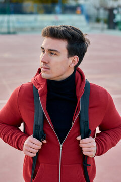 Handsome young student man with a backpack looks to the side