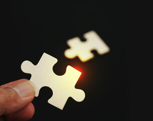 Concept of business,hand holding a puzzle piece on puzzle background. Teamwork is collaborative effort of team to achieve goal or complete mission.	
