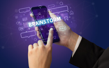 Obraz premium Female hand typing on smartphone with BRAINSTORM inscription, social media concept