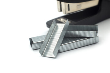 Closeup of staples pile and black slaper on white background