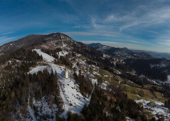 Aerial drone view of Catholic church of Holy Ahacij in Kalise, Slovenia on a sunny winter day with some snow visible. Cold but warm feeling.