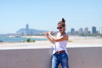 Woman with ponytail playing a flute while standing outdoors