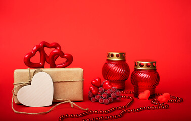 Gift in craft paper, red hearts with red candlesticks, beads on a red background