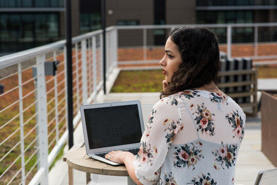 Woman looking off frame sitting at table with laptop