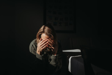 Woman with head in hands with dark background