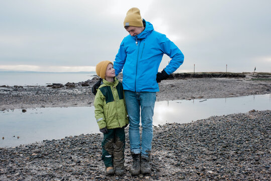 father and son stood together at the beach covered in mud smiling