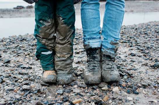 father and sons legs covered in mud after a walk by the sea together