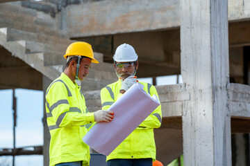 Architect working with blueprints on a building construction site,sketching a construction project.