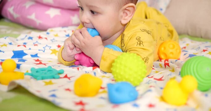 infant, childhood concept - close-up of smiling happy Baby plays with a teether. Teeth cutting. First teeth. Joy toothless 7 months baby bite, gnaws teether toy