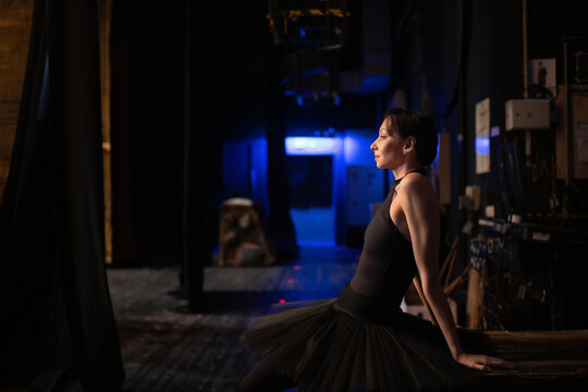 Adult ballerina sitting behind stage - Powered by Adobe