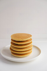 Freshly cooked soft delicious gluten free pancakes stacked on white plate, close up. Space for text. Healthy sweet food.