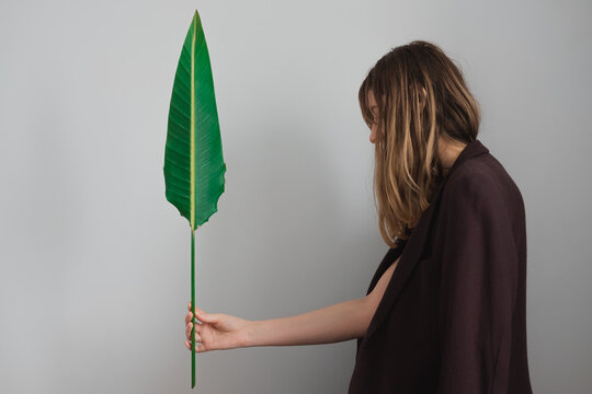 Woman wearing jacket  posing with a green palm leaf.