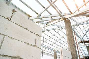 Aerated brick wall and steel roof frame in the construction site,Construction concept.