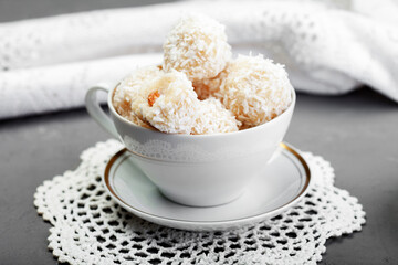 Candies in plate covered by chocolate and shredded coconut on rustic wooden background. Homemade date truffle creamy balls with coconut flakes. Holiday romantic gift to girl, woman. Macro, copy spac