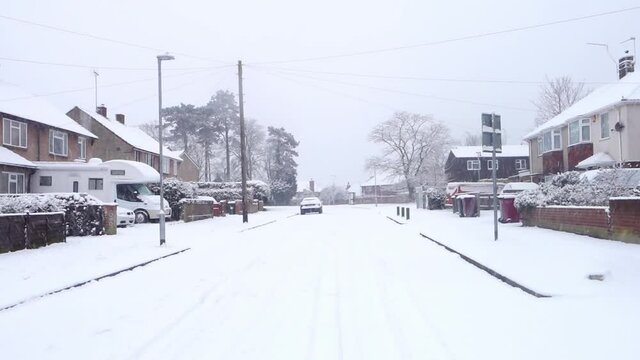 A view down a residential street as snow falls in Reading, UK.