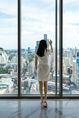Obraz premium Young stylish beautiful woman in a skyscraper in the office against the background of the window, high floor