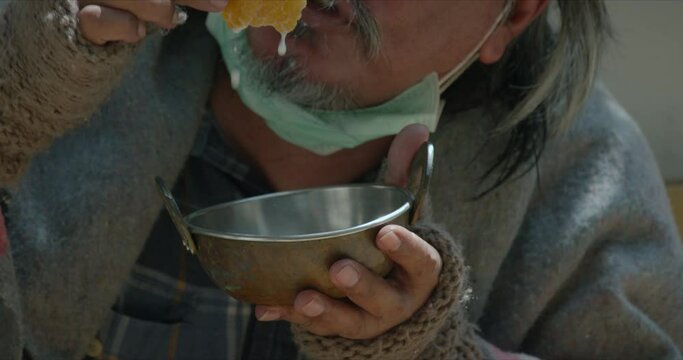 Homeless man getting food from people and eating with happiness