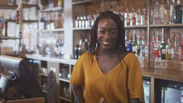 Portrait of smiling female member of bar staff  behind counter - shot in slow motion