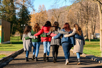 Fototapeta premium Young group of girls walking in autumn park, autumn clothes and autumn walk. Graduation from high school.