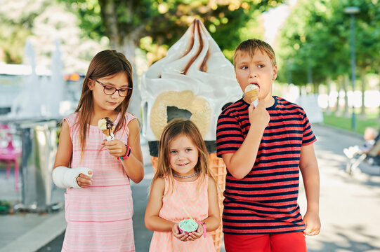Group of 3 funny kids eating ice cream outdoors on a nice sunny day