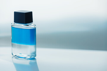 A cosmetic glass bottle of liquid with layers of alcohol and oil, in a state of floating...