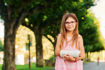 Outdoor portrait of sweet little girl with a cast