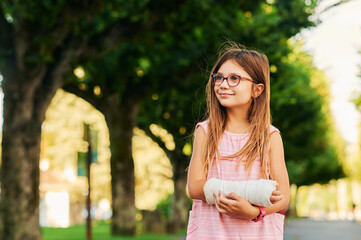 Outdoor portrait of sweet little girl with a cast